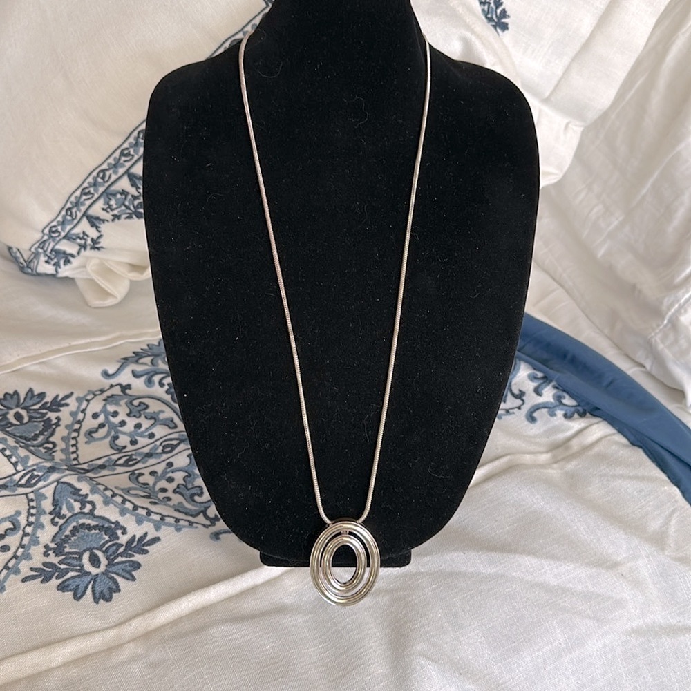 Long snake silver tone chain with oval gold tone abstract pendant